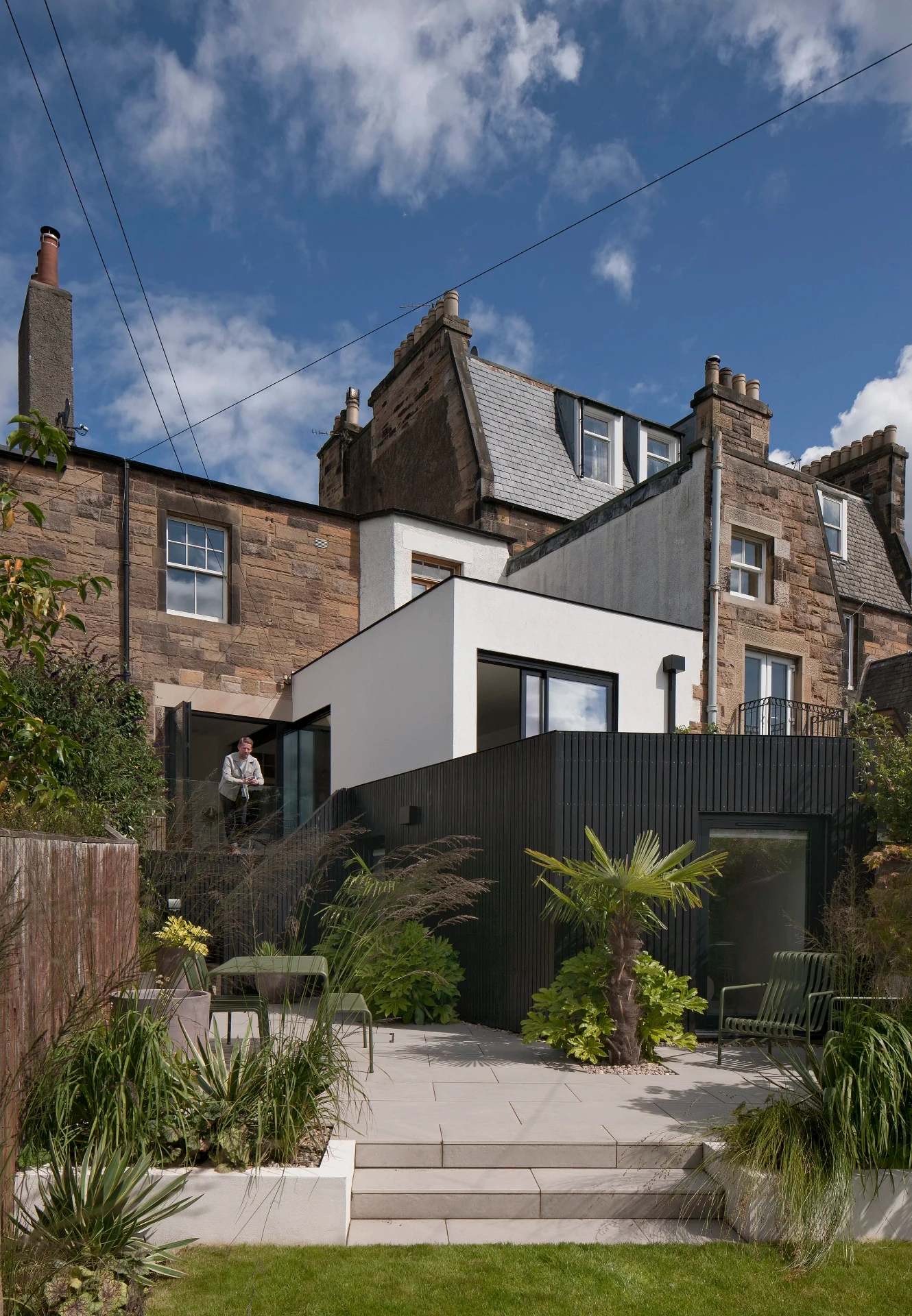 Black timber-clad lower-ground extension to a stone terrace in Craiglockhart, Edinburgh, with landscaped garden terrace