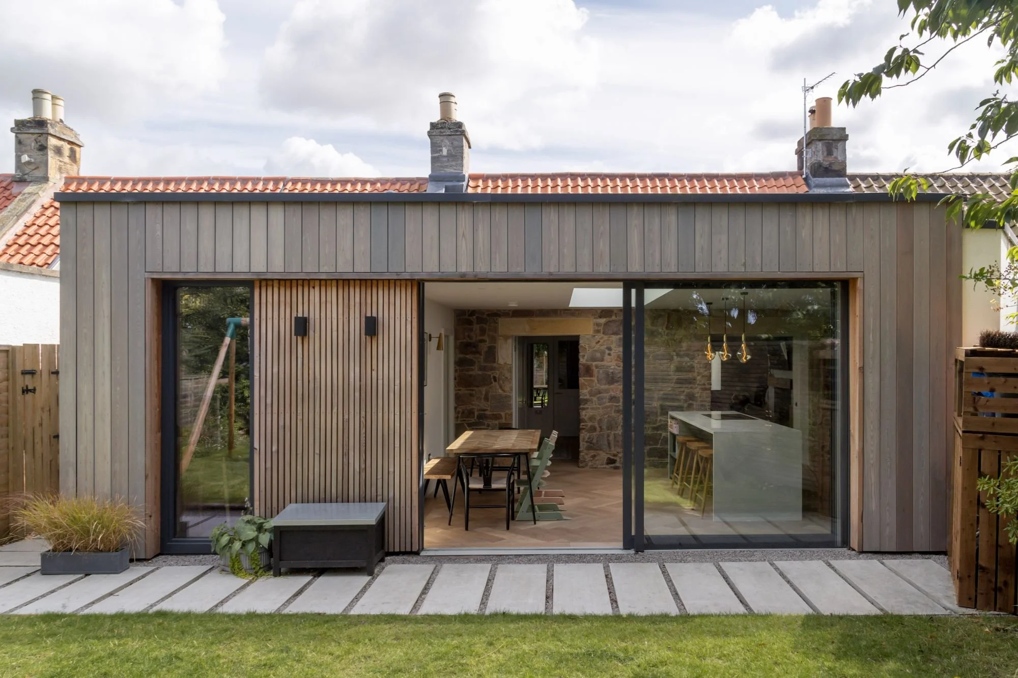 Timber-clad rear extension with full-width glazing at a renovated farm cottage in Drem, East Lothian